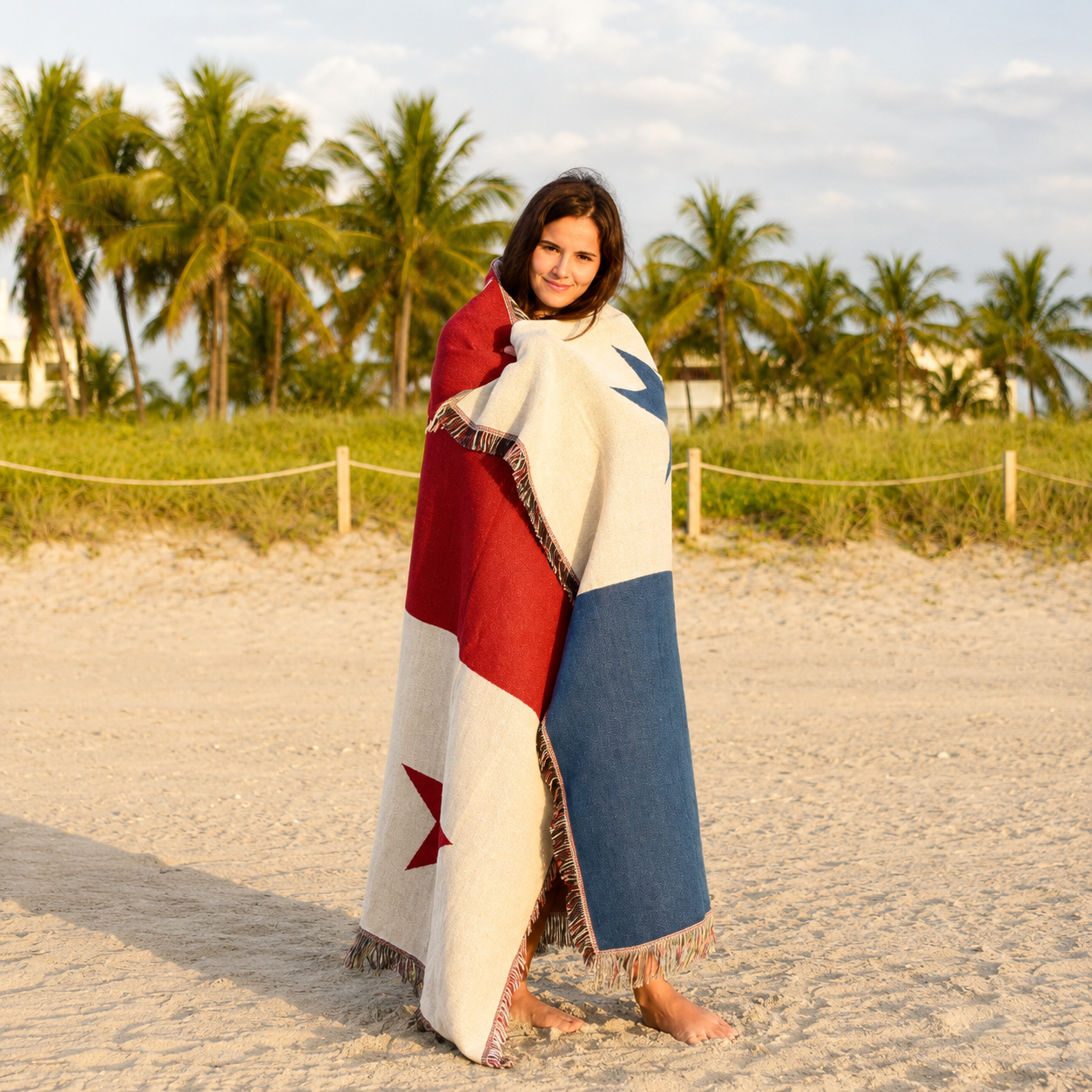 A woman standing on a sandy beach wrapped in Panamá woven throw blanket Ceibo House