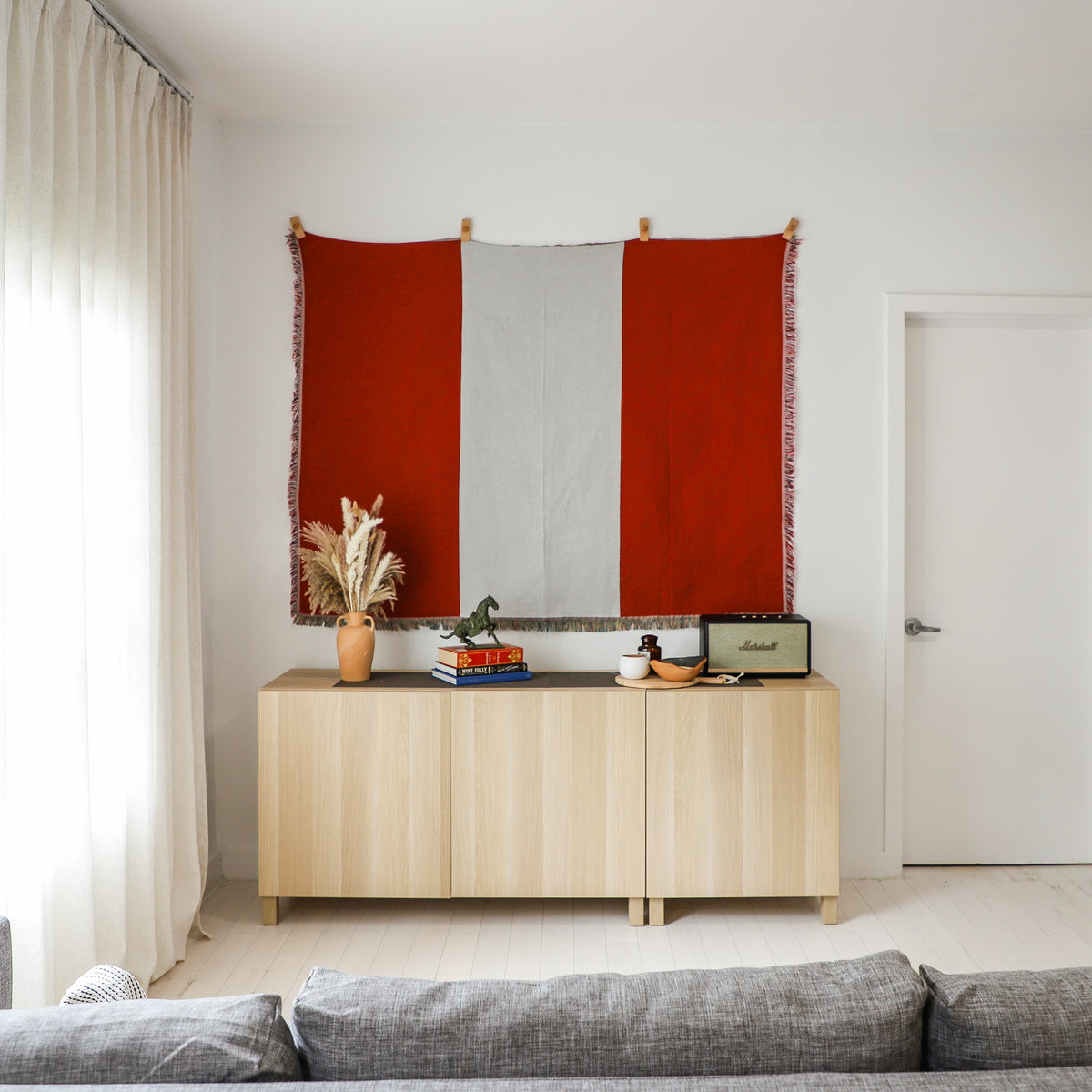 Peru flag woven throw blanket hung as a wall tapestry with wooden hangers above a sideboard