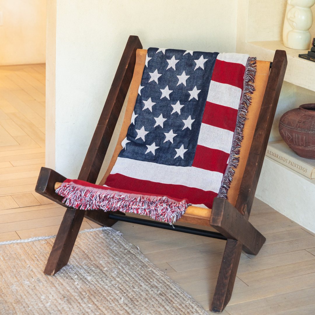 American flag woven throw blanket draped over a wooden lounge chair