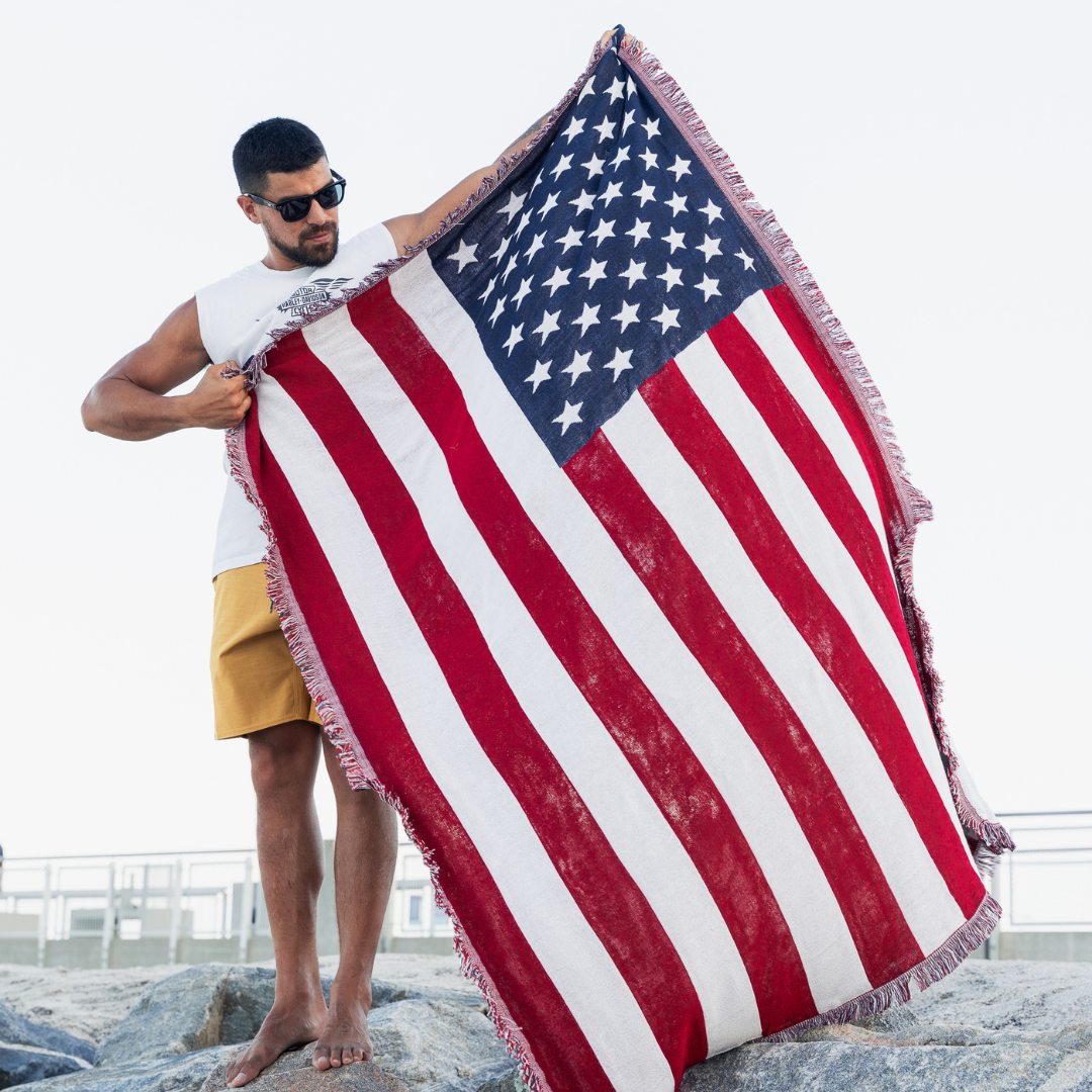 Man holding open the American flag woven throw blanket outdoors